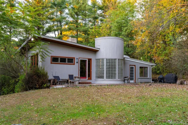 a backyard of a house with table and chairs with plants and wooden fence
