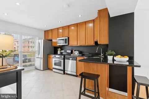 a kitchen with stainless steel appliances granite countertop a refrigerator a stove a sink a dining table and chairs