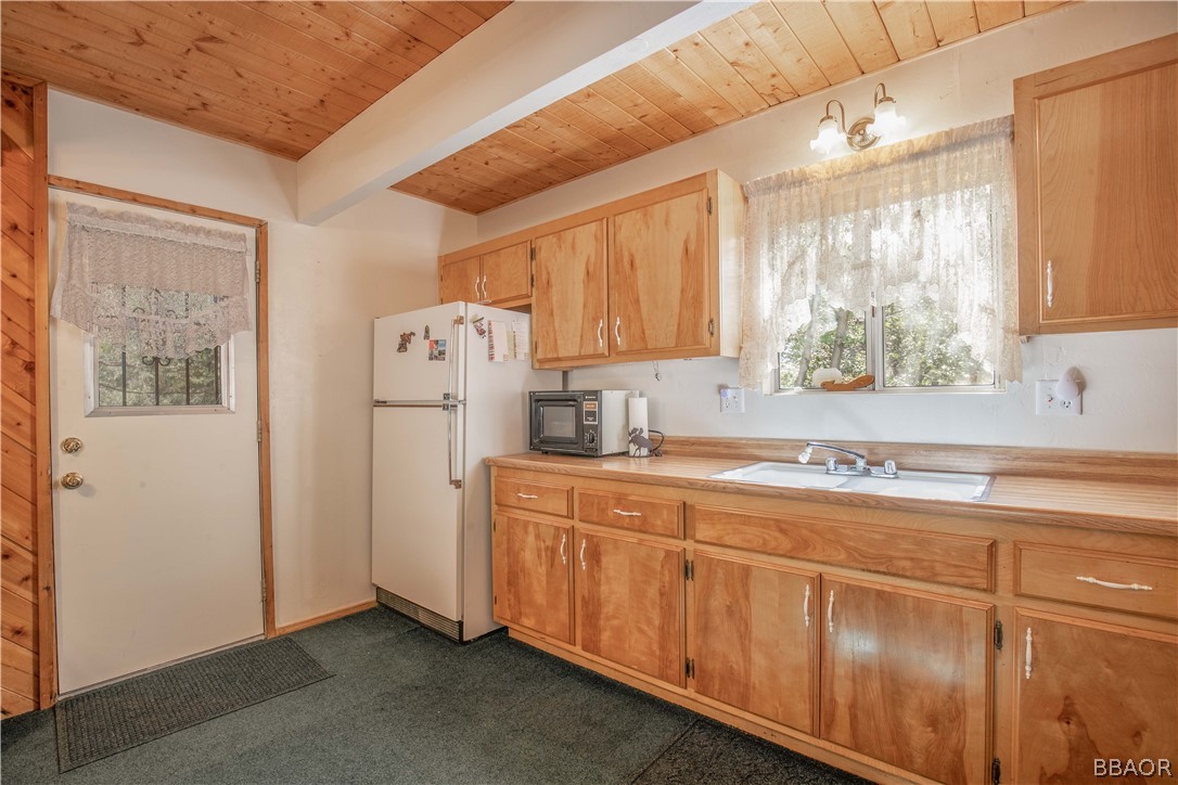 753 Maple Lane Sugarloaf, CA 92386 - Photo 17 of 42 a kitchen with stainless steel appliances granite countertop a refrigerator a sink dishwasher and white cabinets with wooden floor
