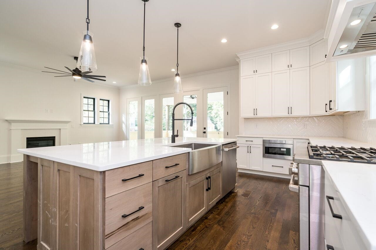 303 Shepherd Street Raleigh, NC 27607 - Photo 11 of 29 a kitchen with kitchen island granite countertop a stove a sink a center island a refrigerator and a wooden floor