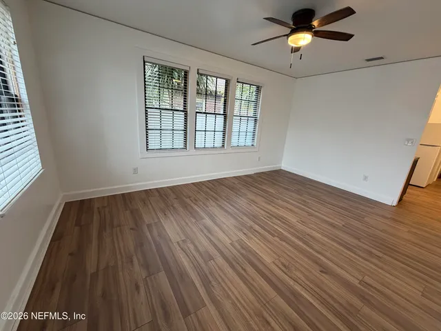an empty room with wooden floor and windows