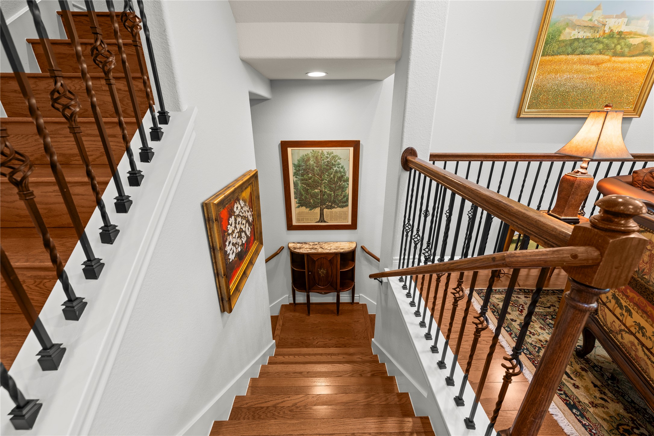 204 Adams Street Georgetown, TX 78628 - Photo 2 of 33 Elegant hardwood stairs with ornate wrought iron railings lead to a well-lit lower landing.