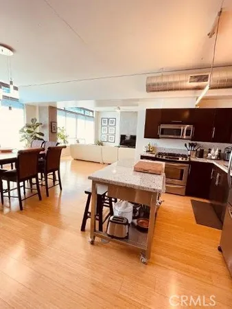 a kitchen with stainless steel appliances kitchen island granite countertop a table chairs and a stove