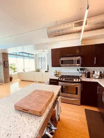 a kitchen with stainless steel appliances granite countertop a stove top oven a sink dishwasher a dining table and chairs with wooden floor