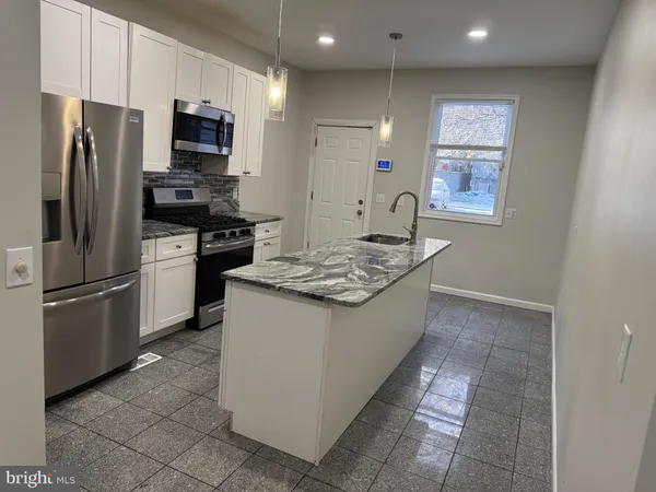 a kitchen with stainless steel appliances granite countertop a refrigerator a stove a sink and a refrigerator