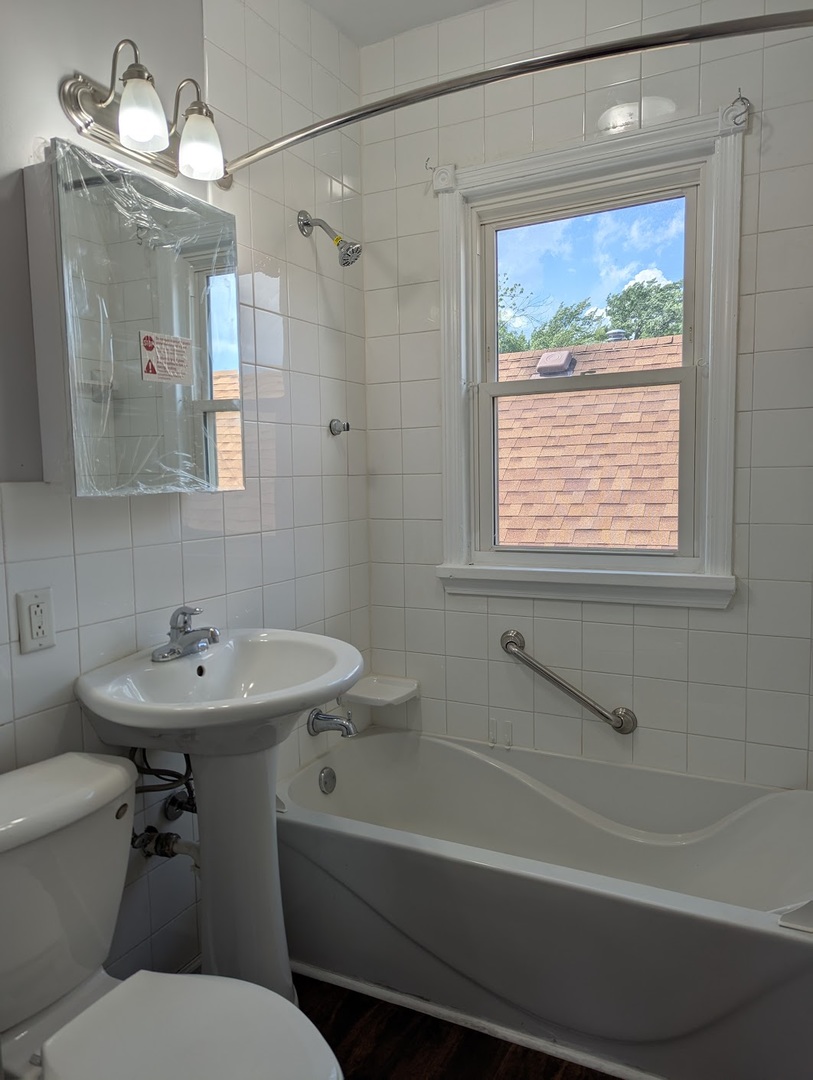 8817 South Elizabeth Street Chicago, IL 60620 - Photo 4 of 17 a bathroom with a sink a mirror a toilet and a bathtub