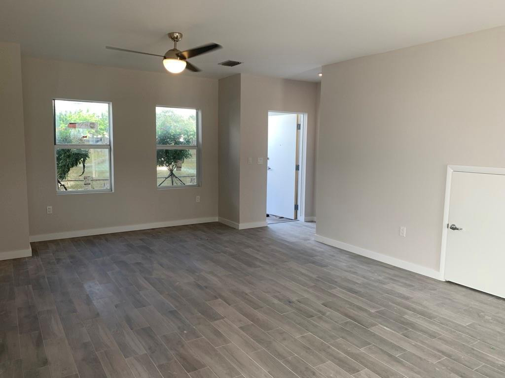 309 Foster Road, Unit 7 Hallandale Beach, FL 33009 - Photo 38 of 53 an empty room with wooden floor chandelier fan and windows