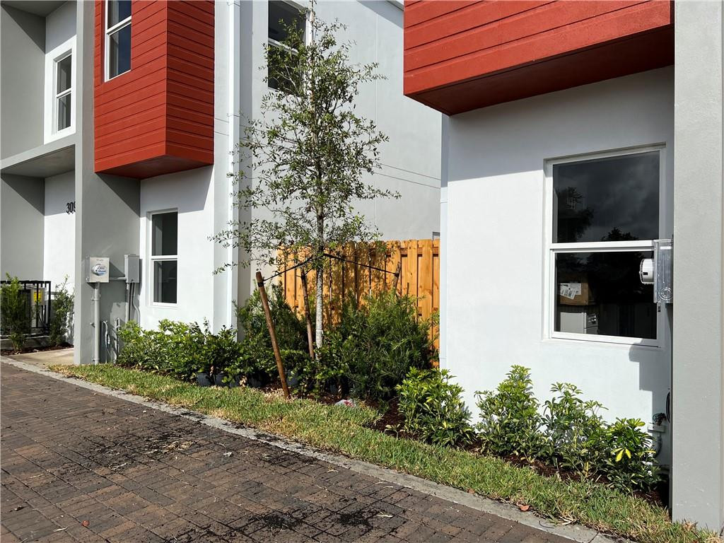 309 Foster Road, Unit 7 Hallandale Beach, FL 33009 - Photo 6 of 53 a view of a backyard with plants and brick wall