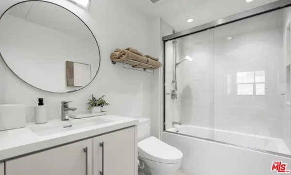 a bathroom with a toilet a sink a mirror a vanity and shower