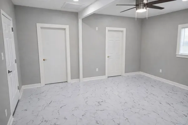 a view of an empty room and chandelier fan