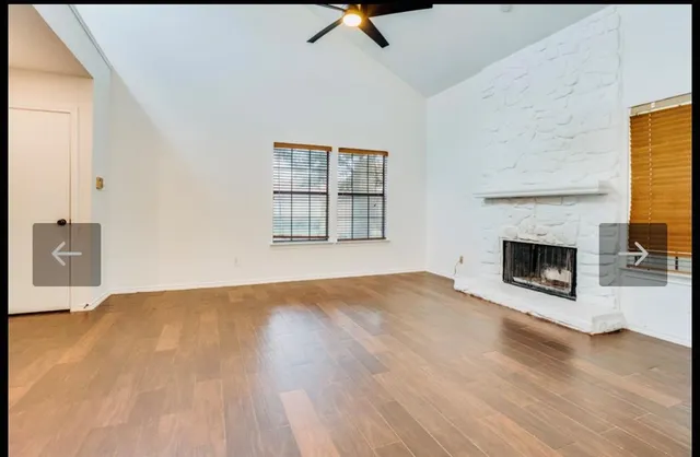 a view of empty room with wooden floor and fireplace