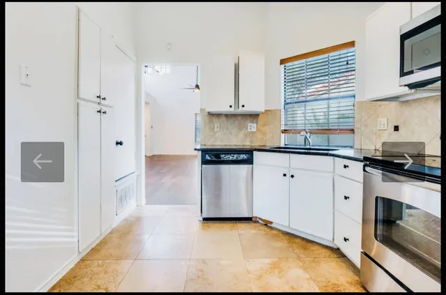 a kitchen with granite countertop white cabinets and white appliances