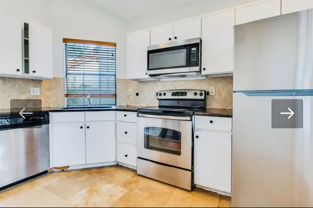 a kitchen with granite countertop white cabinets stainless steel appliances and a sink