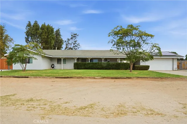 a front view of a house with a garden and a tree