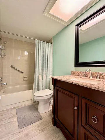 a living room with stainless steel appliances kitchen island granite countertop a refrigerator and a wooden cabinets