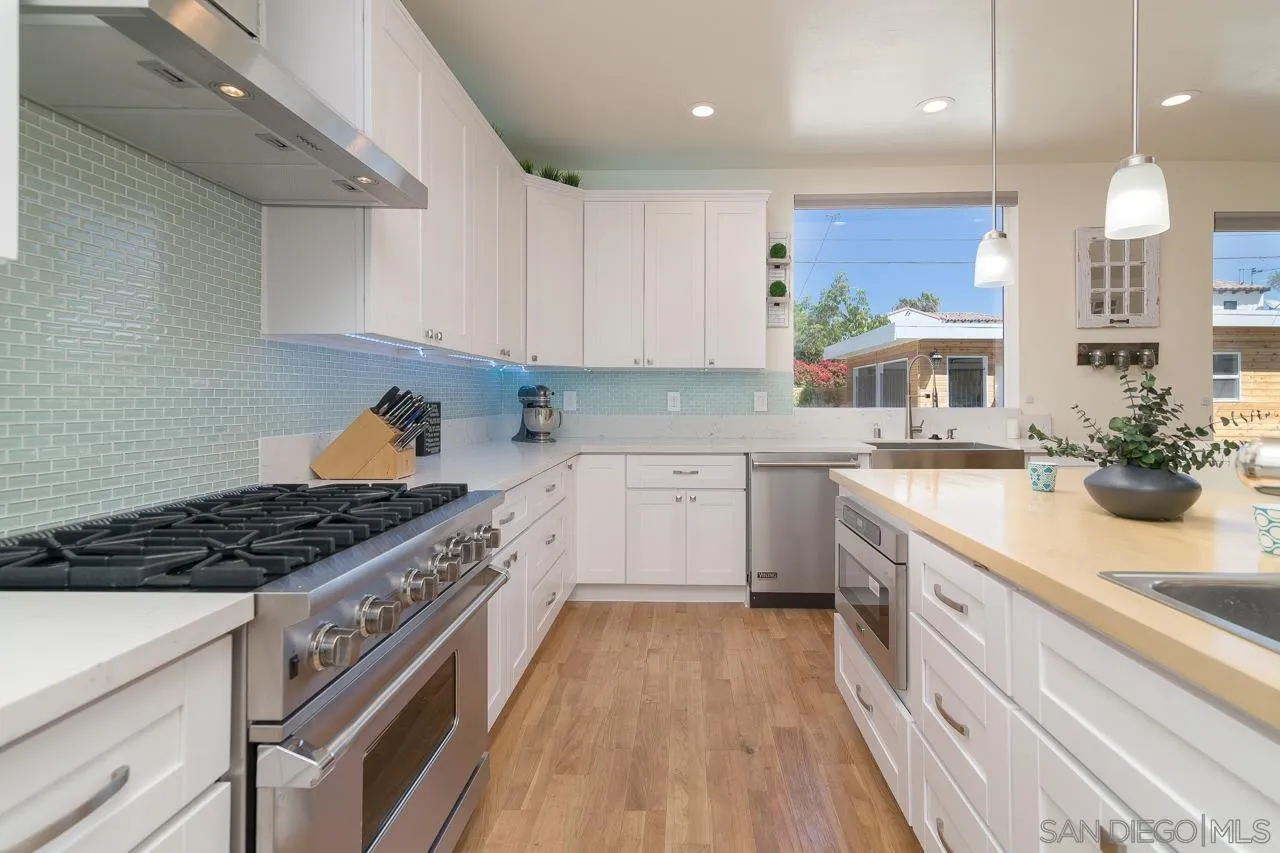 1220 Emerald Street San Diego, CA 92109 - Photo 4 of 19 a kitchen with stainless steel appliances granite countertop a sink stove and cabinets