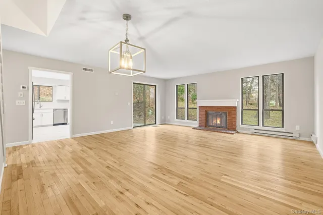 a view of empty room with wooden floor and fireplace