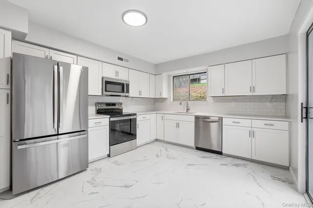 a kitchen with granite countertop white cabinets and stainless steel appliances