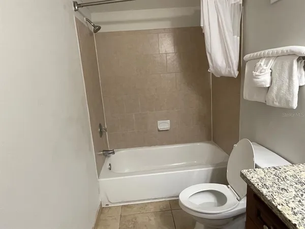 a bathroom with a granite countertop bathtub sink vanity mirror and toilet