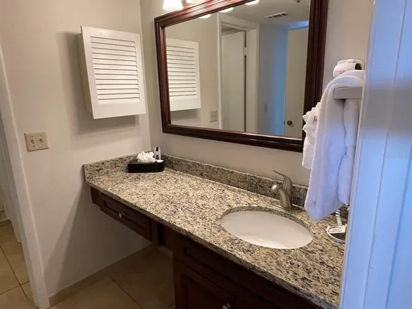 a bathroom with a granite countertop sink and a mirror