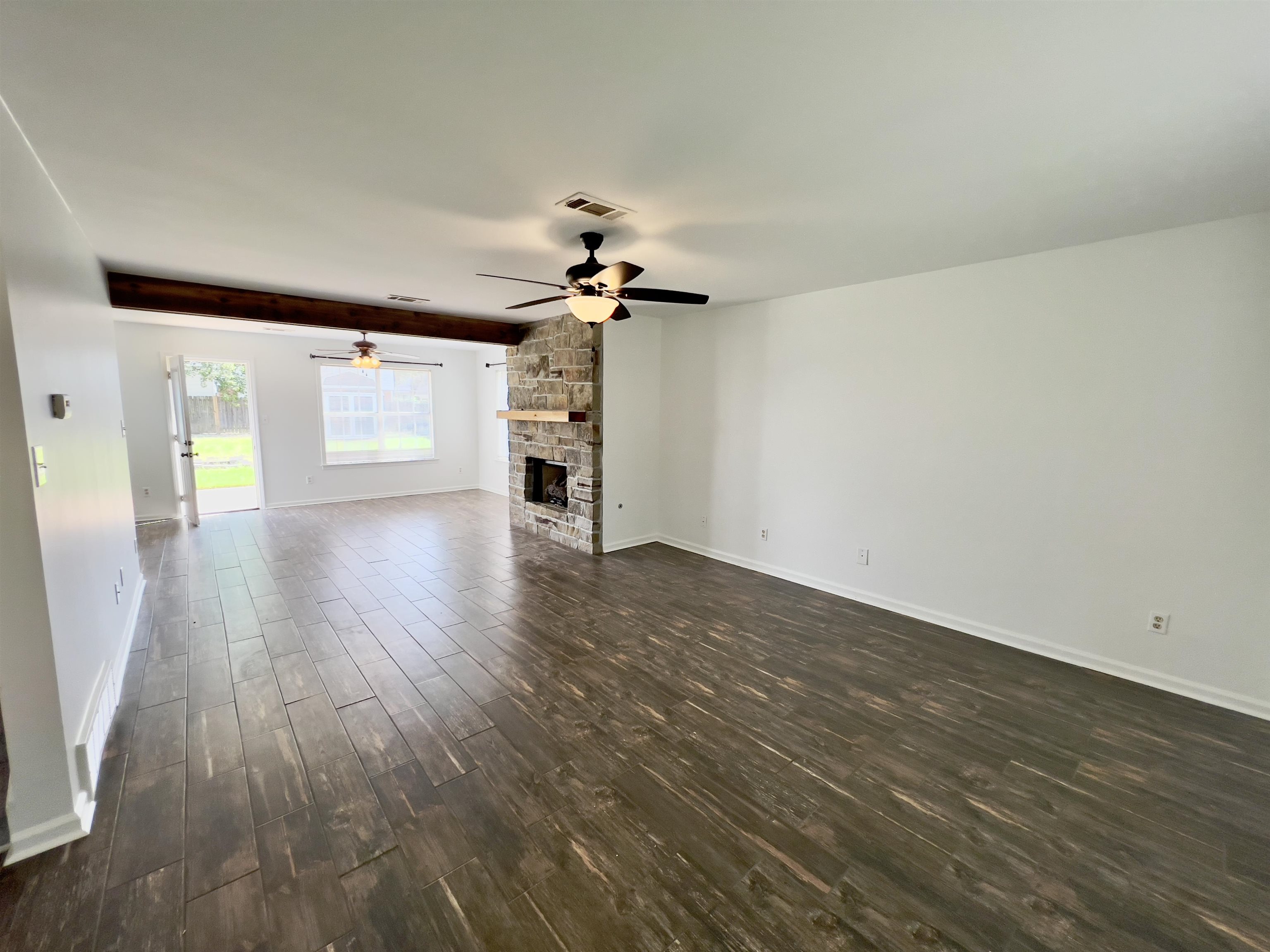 251 Cross Point Cove Collierville, TN 38017 - Photo 3 of 17 Unfurnished living room featuring a fireplace, ceiling fan, dark hardwood / wood-style flooring, and beamed ceiling