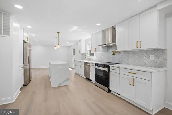 a large kitchen with granite countertop a large counter top a sink stainless steel appliances and cabinets