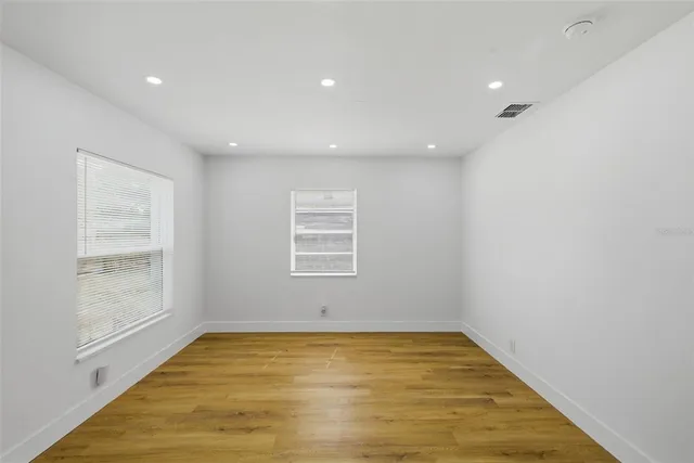 an empty room with wooden floor and windows
