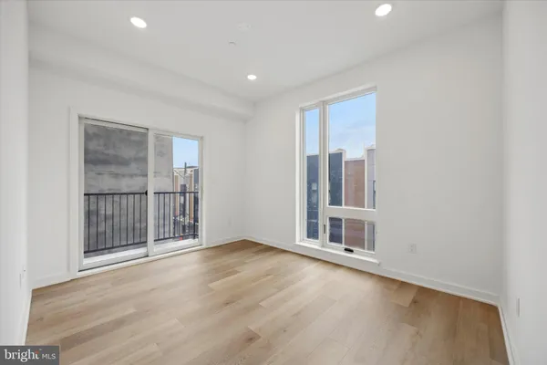 a view of an empty room with wooden floor and fan