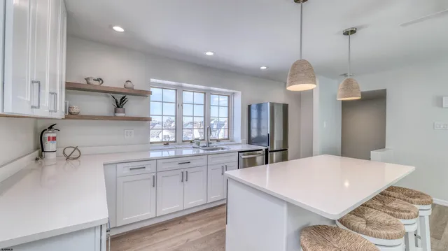 a kitchen with stainless steel appliances granite countertop a sink a stove a refrigerator and island with wooden floor