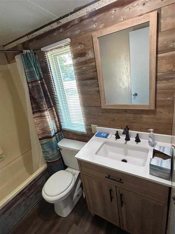 4705 Fox Hollow Road Graham, TX 76450 - Photo 15 of 28 Full bath featuring wooden walls, vanity, wood finished floors, and shower / bathtub combination with curtain