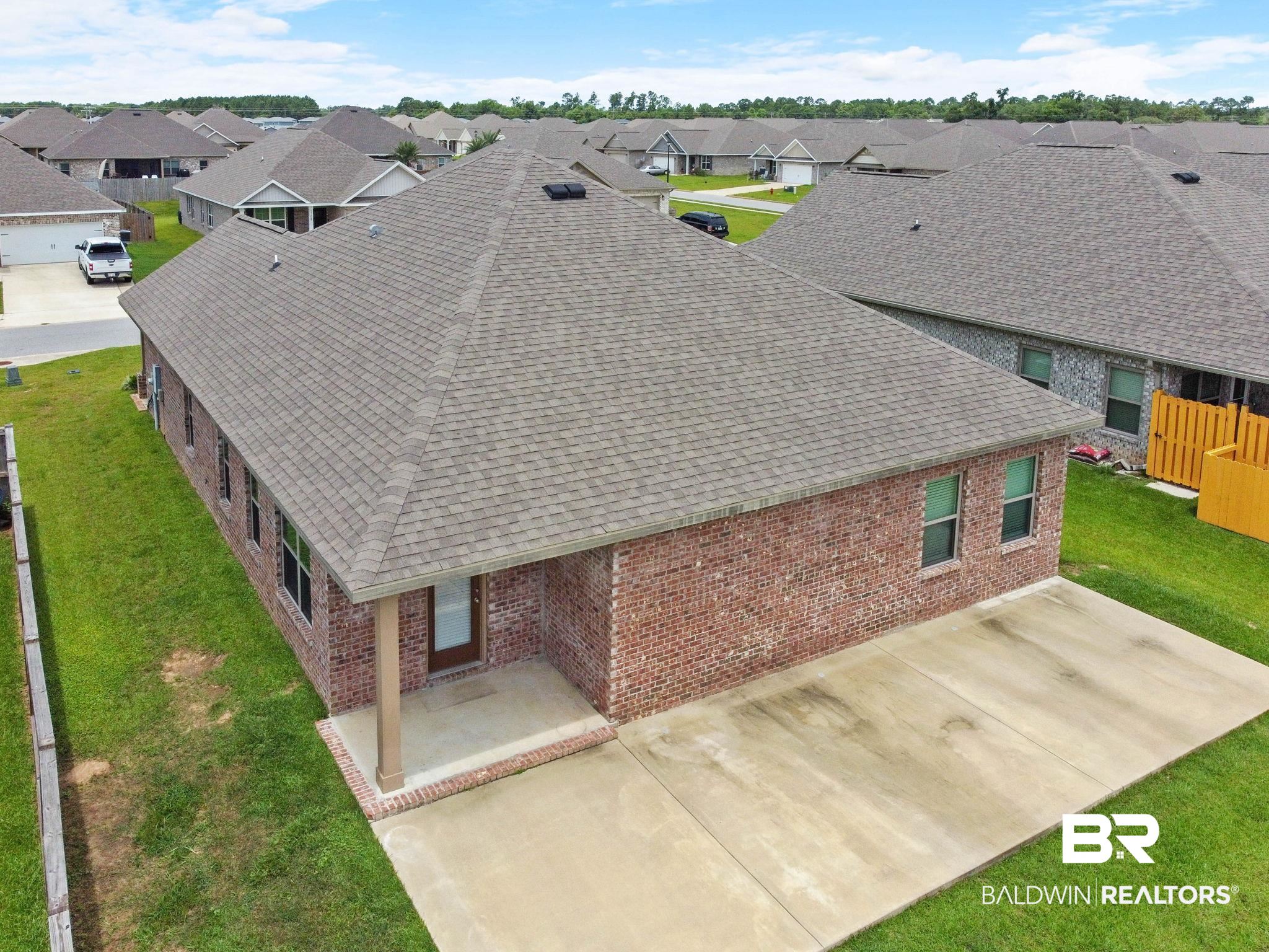 1710 Grouse Street Foley, AL 36535 - Photo 76 of 76 Brick exterior home featuring a gabled shingle roof, multiple windows, a covered entry porch with a column, and a concrete patio