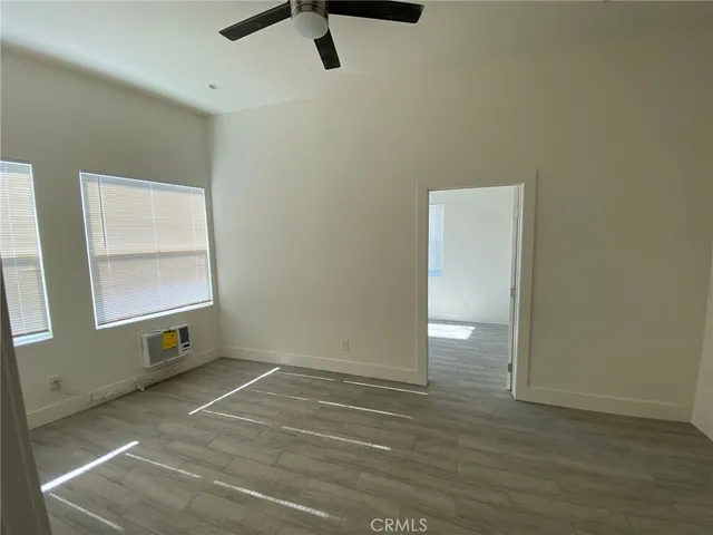 an empty room with wooden floor cabinet and windows
