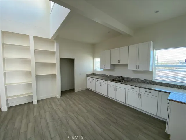 a kitchen with granite countertop white cabinets and wooden floors