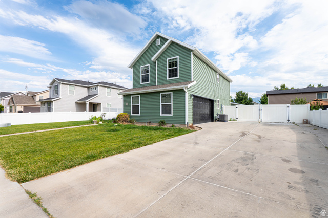 1443 West 250 North Springville, UT 84663 - Photo 4 of 23 Two-story residence featuring green siding, a black garage door, and white trim windows