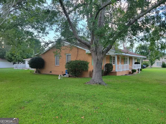 a front view of house with a garden and trees