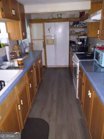 a kitchen with sink a refrigerator and wooden cabinets