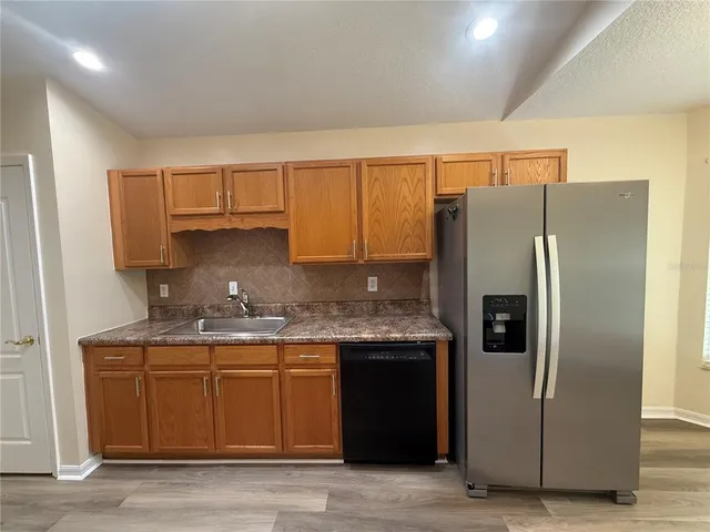 a kitchen with stainless steel appliances granite countertop a refrigerator a sink and a stove