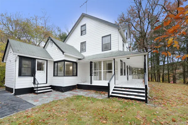 a white house that has a wooden bench next to a road