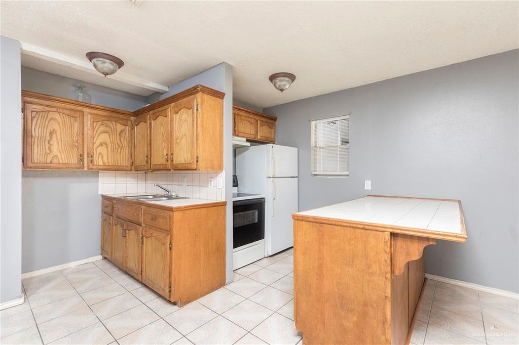 3417 North Kenyon Road Edinburg, TX 78542 - Photo 3 of 12 a kitchen with stainless steel appliances granite countertop a refrigerator a sink dishwasher a stove with wooden cabinets and floor