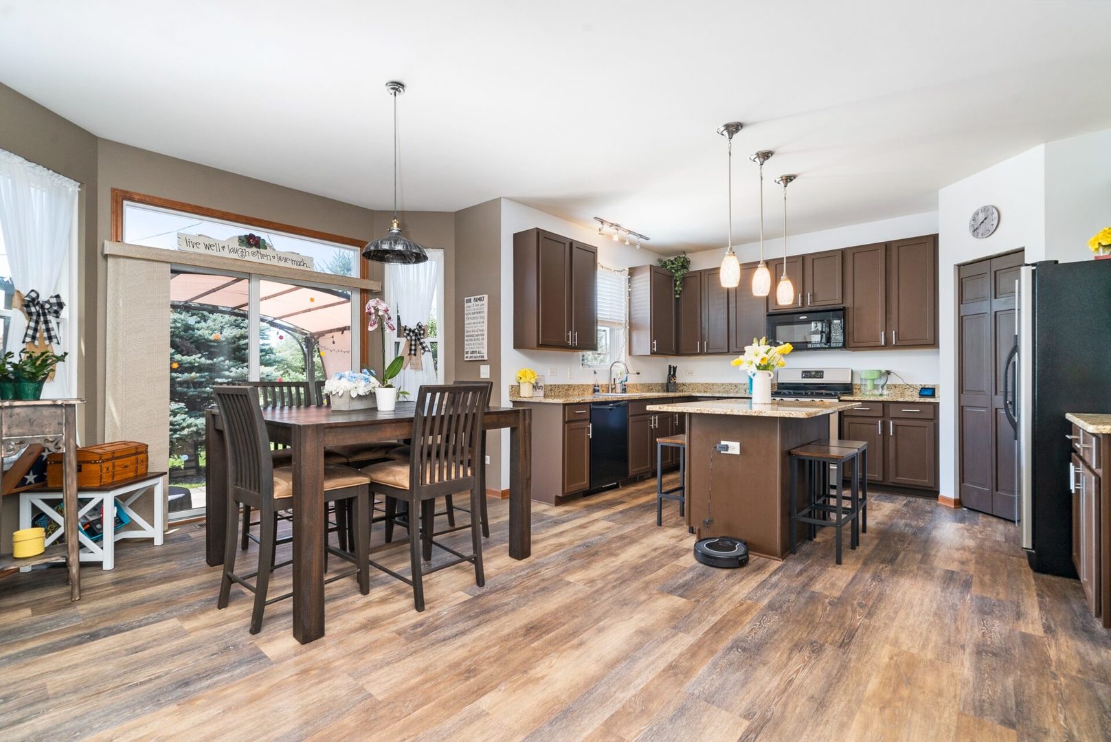 25362 Spring Street Manhattan, IL 60442 - Photo 3 of 28 a kitchen with a table chairs refrigerator and microwave