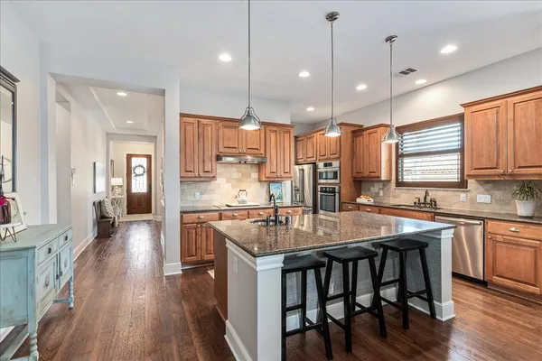 a kitchen with stainless steel appliances granite countertop table chairs stove refrigerator and cabinets