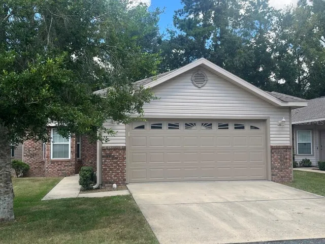 a view of a white house with a small yard plants and large tree