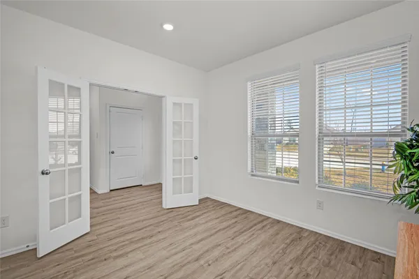 a view of an empty room with wooden floor and windows