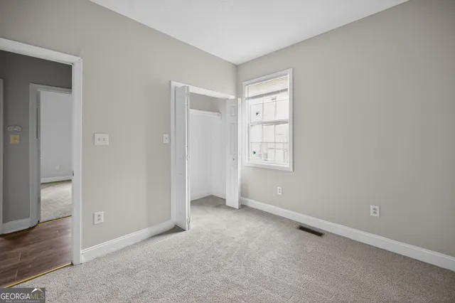 an empty room with wooden floor closet and windows