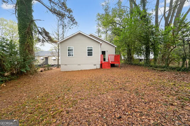 a view of backyard of house with wooden fence and trees
