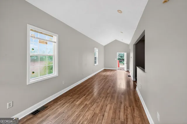 a view of a big room with wooden floor and windows