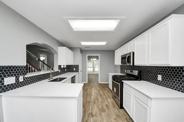 a kitchen that has a sink a stove and a wooden floors