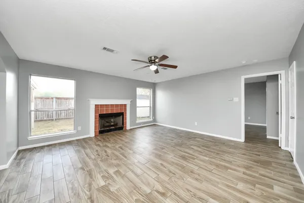 wooden floor fireplace and windows in an empty room