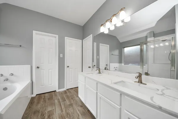 a spacious bathroom with a double vanity sink mirror and bathtub