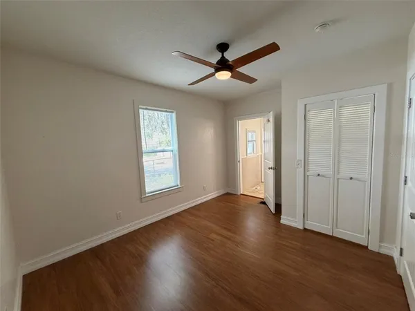 a view of an empty room with wooden floor and a window